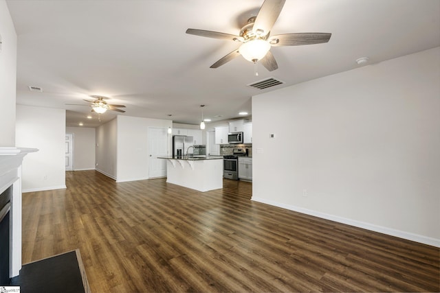 unfurnished living room with a fireplace, dark wood finished floors, baseboards, and ceiling fan