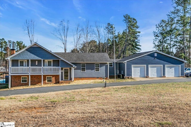 view of front of home featuring an attached garage, driveway, an outdoor structure, and a front yard