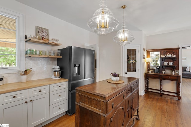 kitchen featuring tasteful backsplash, butcher block countertops, light wood-style floors, and stainless steel fridge with ice dispenser