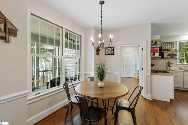 dining space with an inviting chandelier, baseboards, and wood finished floors