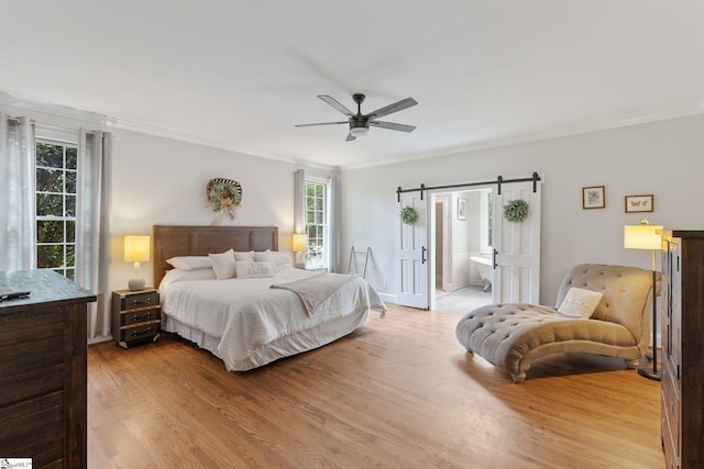 bedroom with crown molding, a barn door, and light wood-style floors