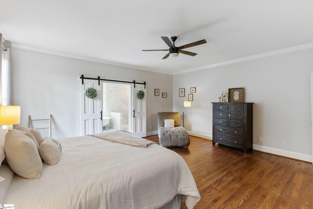 bedroom with wood finished floors, crown molding, baseboards, and a barn door