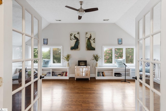 interior space with french doors, visible vents, vaulted ceiling, and wood finished floors