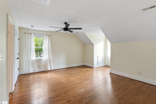 bonus room with a textured ceiling, baseboards, vaulted ceiling, and wood finished floors