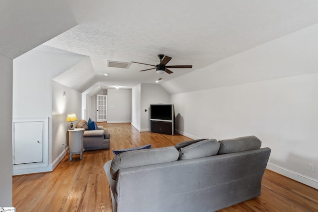 living room with light wood-type flooring, visible vents, vaulted ceiling, and baseboards