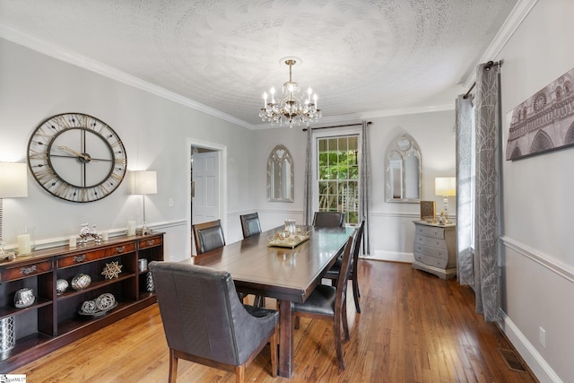 dining area featuring a textured ceiling, hardwood / wood-style floors, a notable chandelier, and crown molding