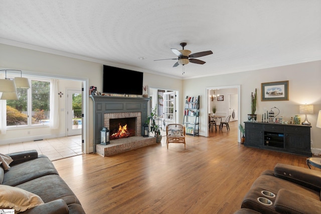 living area with ceiling fan, ornamental molding, a fireplace, and wood finished floors