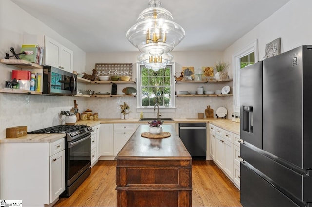 kitchen with stainless steel appliances, a sink, light wood-type flooring, decorative backsplash, and open shelves