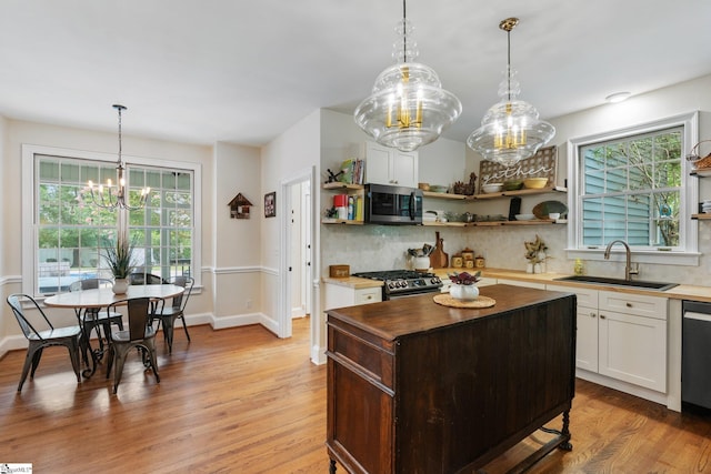 kitchen featuring stainless steel appliances, open shelves, butcher block countertops, and a sink