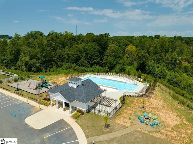 view of swimming pool featuring a fenced in pool, fence, and a view of trees