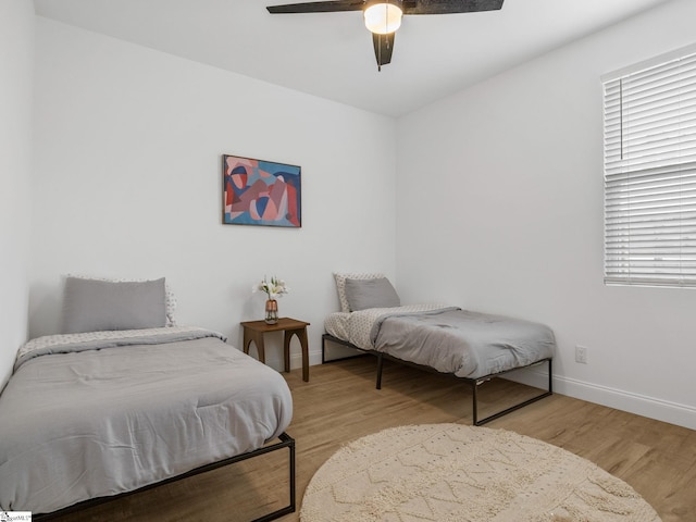 bedroom featuring a ceiling fan, baseboards, and wood finished floors