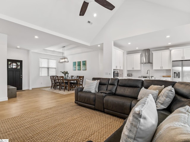 living area featuring light wood-style floors, recessed lighting, high vaulted ceiling, and baseboards