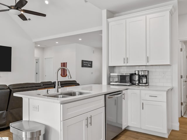 kitchen featuring stainless steel appliances, light countertops, open floor plan, a sink, and vaulted ceiling