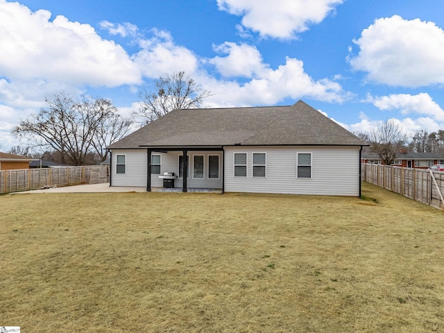 rear view of house featuring a patio area, a fenced backyard, a lawn, and roof with shingles