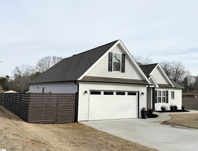 view of front of house featuring driveway, a shingled roof, a garage, and fence