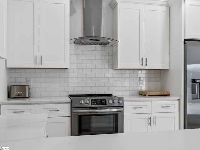 kitchen with light stone counters, stainless steel appliances, white cabinets, wall chimney range hood, and tasteful backsplash