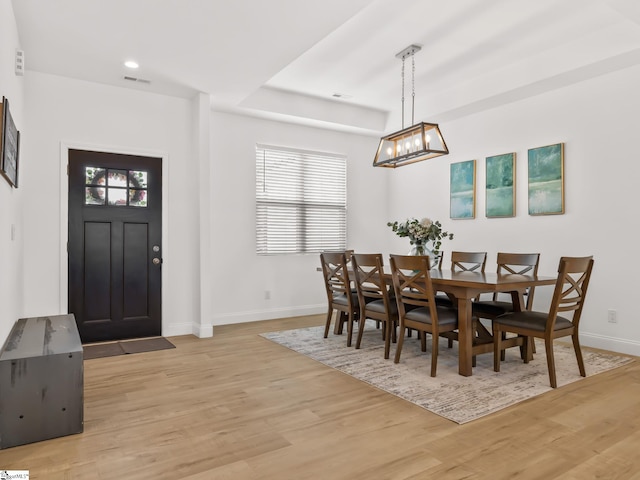 dining room featuring light wood finished floors, plenty of natural light, visible vents, and baseboards