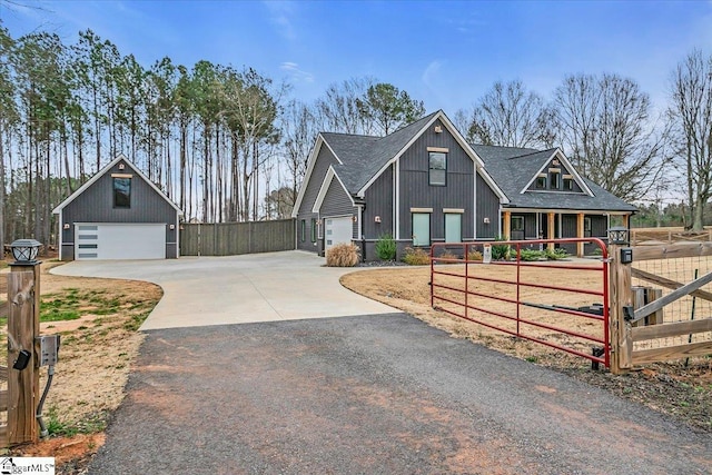 view of front facade with an outbuilding, a shingled roof, a detached garage, and fence