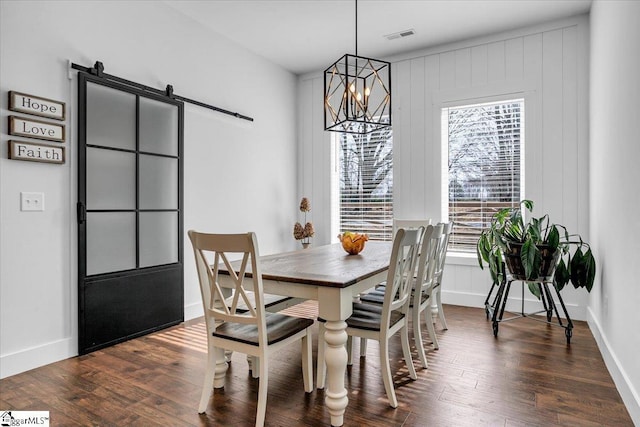 dining space with visible vents, dark wood finished floors, baseboards, and a barn door