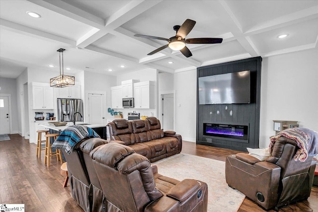 living room featuring dark wood-style floors, a large fireplace, coffered ceiling, and baseboards