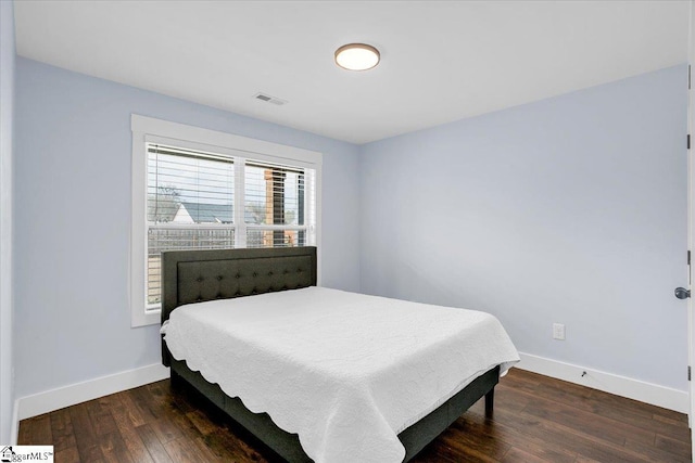 bedroom with hardwood / wood-style flooring, visible vents, and baseboards