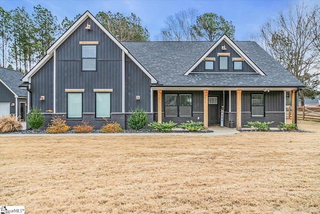 view of front of house featuring covered porch, a front lawn, and roof with shingles