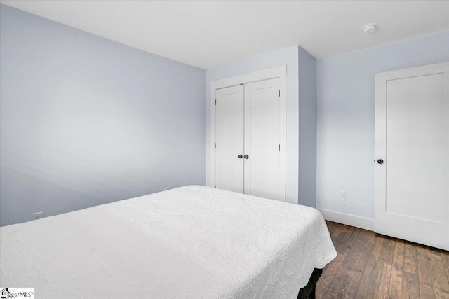 bedroom with a closet, wood-type flooring, and baseboards