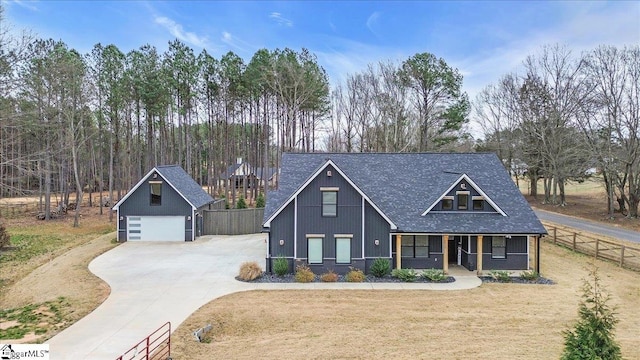 view of front of home with a shingled roof, a front yard, fence, and a detached garage