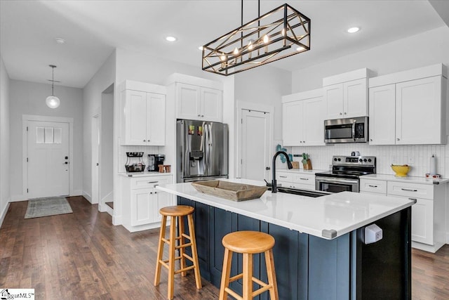 kitchen featuring appliances with stainless steel finishes, a sink, decorative backsplash, and dark wood-style floors