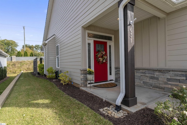 view of exterior entry featuring stone siding and a yard