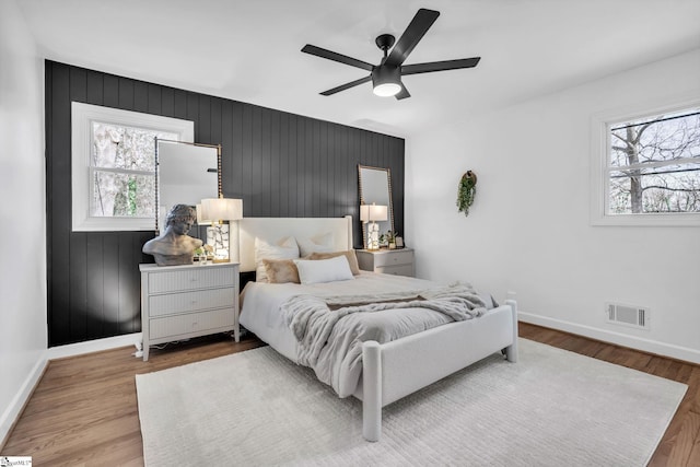 bedroom with multiple windows, visible vents, and wood finished floors