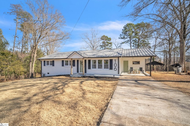 ranch-style home with metal roof, fence, and driveway