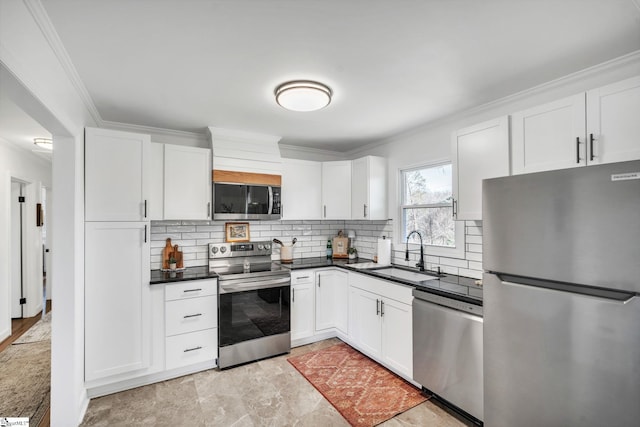 kitchen featuring stainless steel appliances, a sink, white cabinets, dark countertops, and crown molding