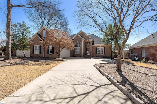 traditional home featuring concrete driveway, roof with shingles, an attached garage, fence, and brick siding