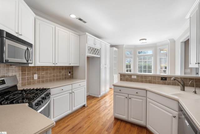 kitchen with stainless steel appliances, a sink, visible vents, white cabinetry, and light countertops