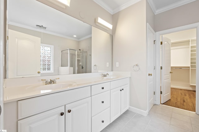 full bathroom with double vanity, a stall shower, ornamental molding, tile patterned floors, and a sink