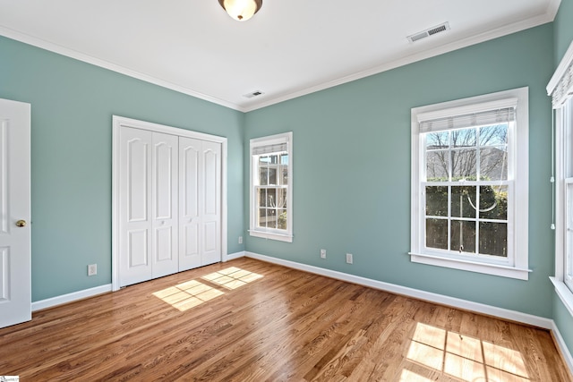 unfurnished bedroom featuring visible vents, crown molding, baseboards, and wood finished floors