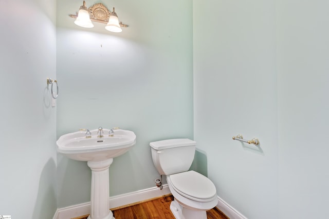 bathroom featuring toilet, a sink, baseboards, and wood finished floors