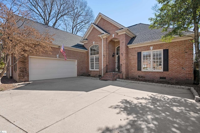 traditional-style home with a garage, brick siding, a shingled roof, driveway, and crawl space