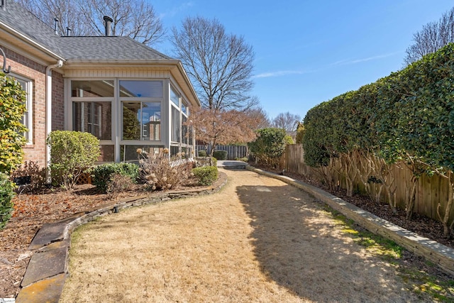 view of yard featuring fence and a sunroom