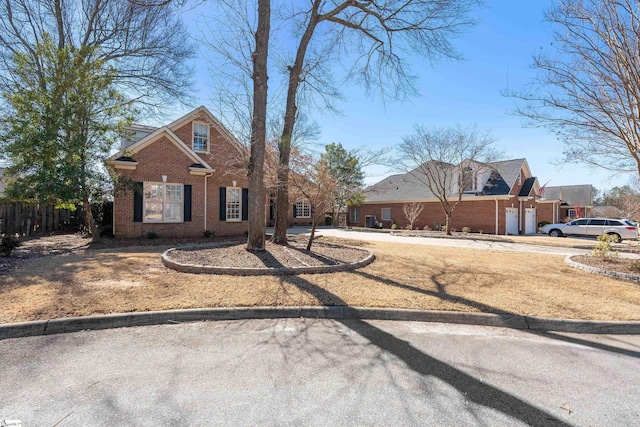 view of front of home with brick siding, fence, and driveway