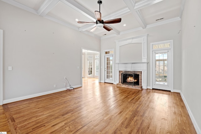 unfurnished living room with baseboards, visible vents, coffered ceiling, light wood-style floors, and a fireplace