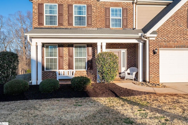 view of front of house with a porch, brick siding, and an attached garage