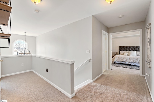 corridor featuring carpet flooring, an upstairs landing, and baseboards