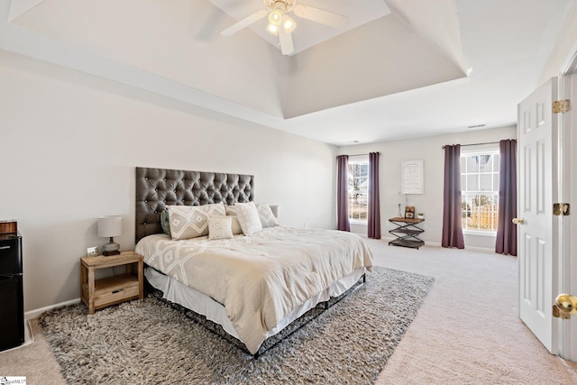 carpeted bedroom featuring a ceiling fan, a tray ceiling, and baseboards