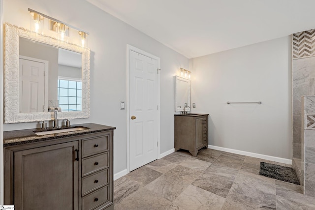 full bathroom featuring two vanities, a sink, and baseboards