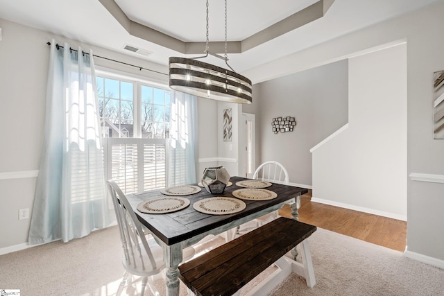 dining area featuring carpet floors, a raised ceiling, visible vents, and baseboards