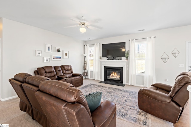 living room featuring carpet, baseboards, a ceiling fan, and a fireplace with flush hearth