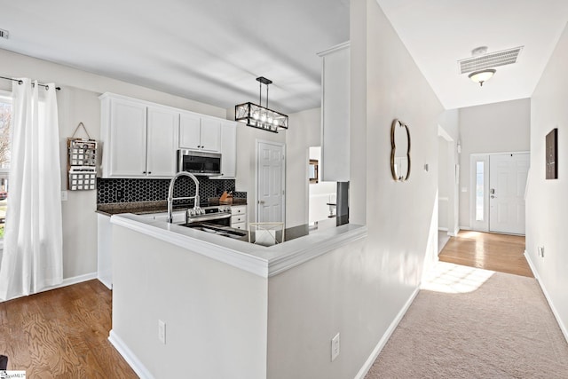 kitchen featuring baseboards, dark countertops, stainless steel appliances, white cabinetry, and backsplash