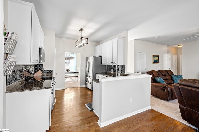 kitchen with dark wood finished floors, open floor plan, stainless steel appliances, white cabinetry, and backsplash